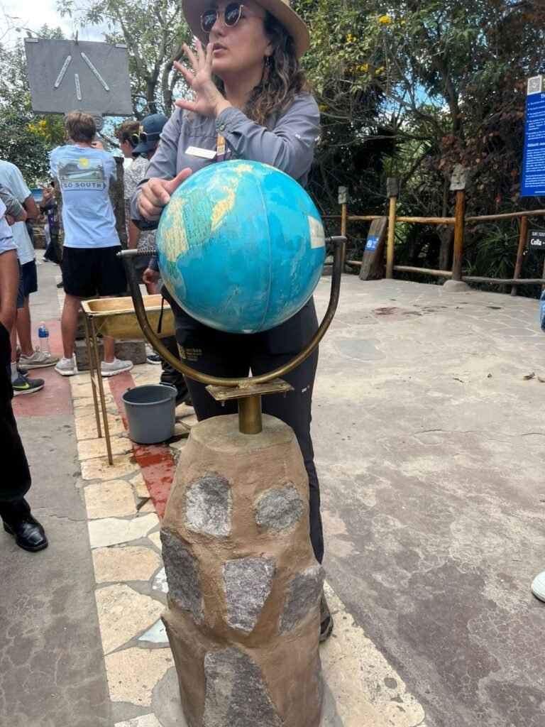 Estudiantes de la Universidad Nacional de Chimborazo junto a la bola del mundo en el Museo Inty Ñan, durante una gira académica organizada por Tour Salinerito.